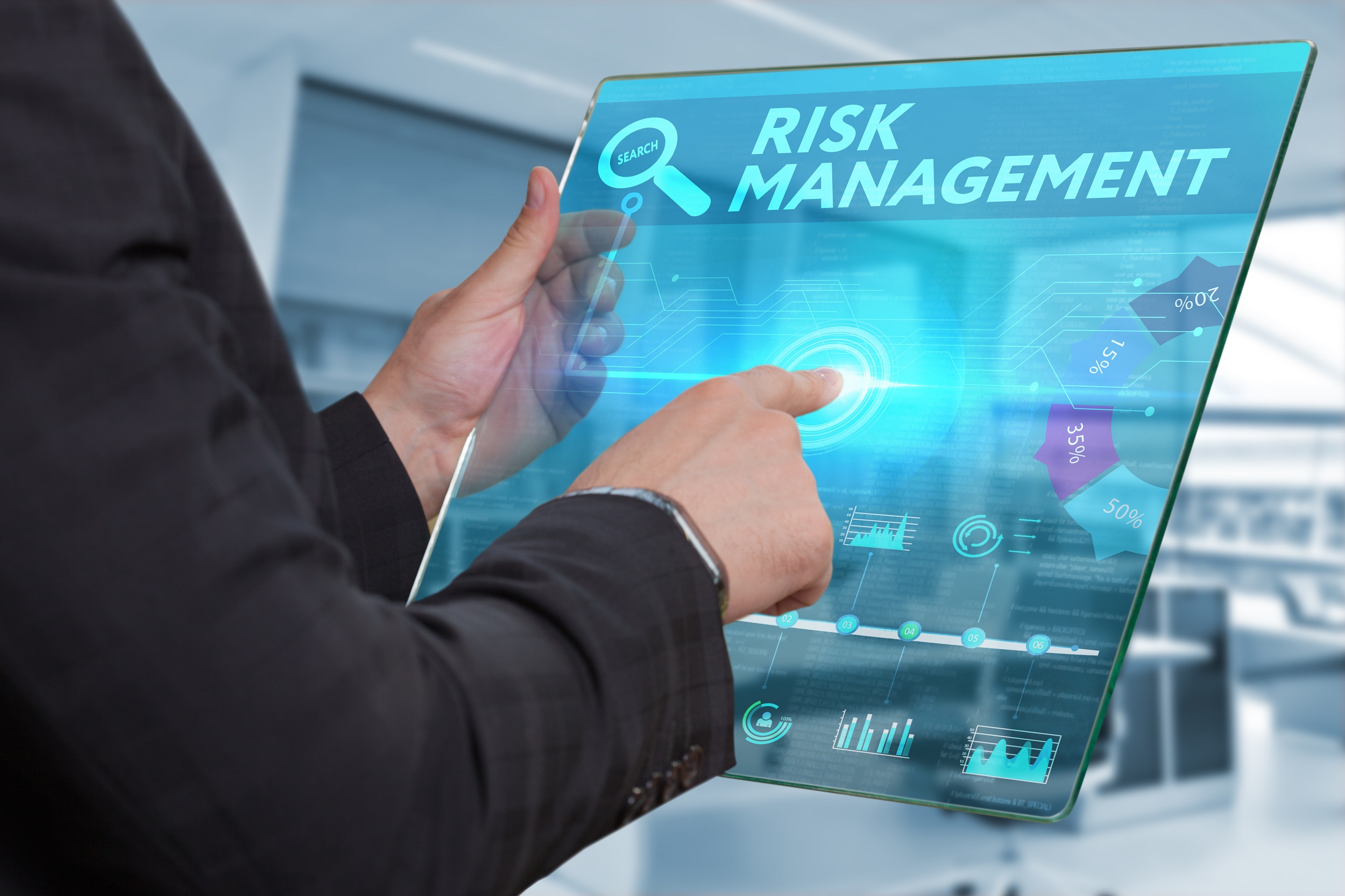 Man holds glass tablet and points to the words 'risk management'