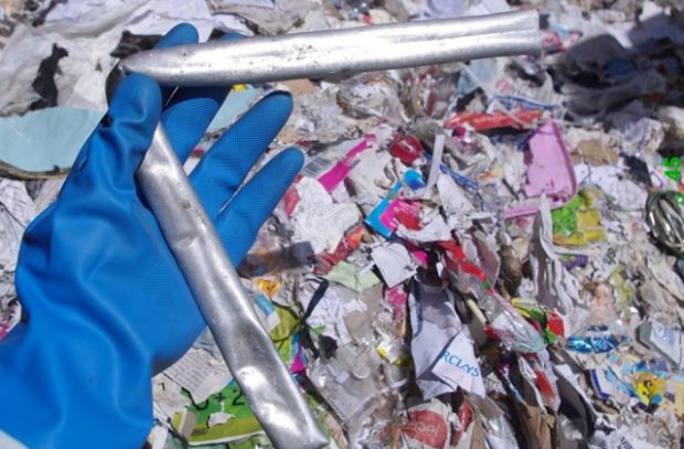 A bent metal pipe held up among waste paper.