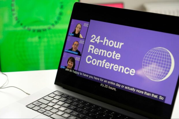 An image of the conference in action on a laptop, there is an international community poster in the background. Kara, Martin, and Clara Greo are seen at the side of the screen presenting during the welcome kick off to the conference.