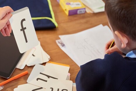 Close up of boy and teacher using phonics flash card