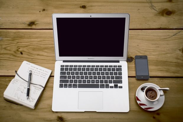 Laptop, papers, phone and a cup of coffee at a desk