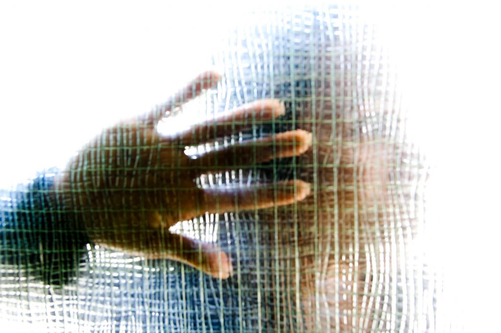 Woman with hand to glass panel in a front door