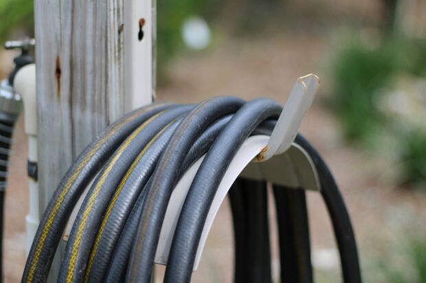 A hosepipe stored on a hook outdoors.