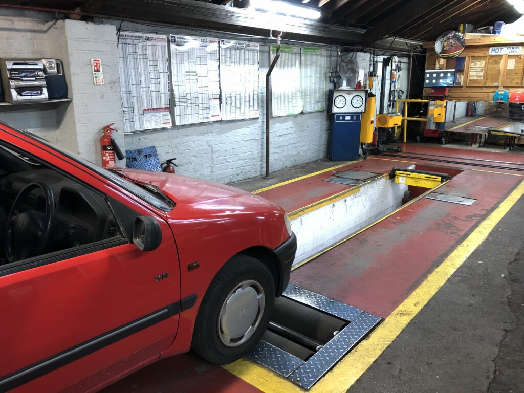 Car in MOT test centre approaching a roller brake tester