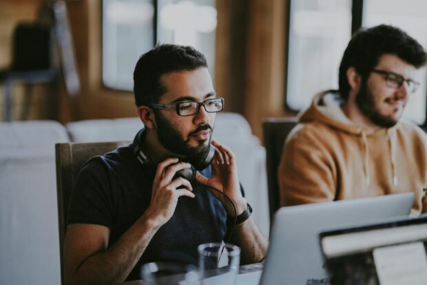 Two men sitting in front of computers.