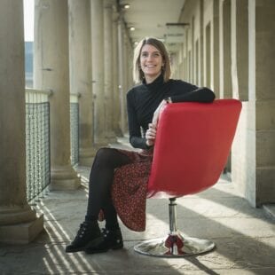 Chloe Williams sitting in a red chair on a balcony