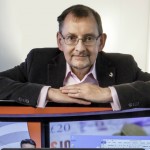 Dr Andy Harter leaning on a computer monitor.