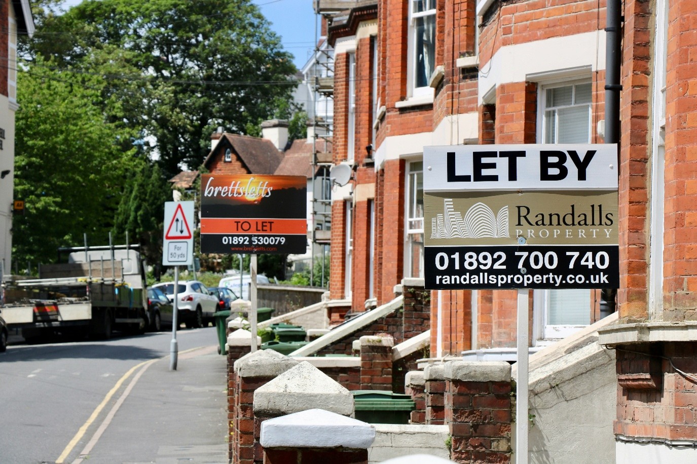 Photograph of a row of houses with two "To Let" signs in the foreground.