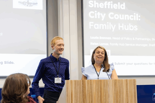 Two members of the Sheffield demonstrator pilot team, Laurie and Helen presenting on family hubs at our first Test, Learn and Grow event. Laurie and Helen are standing next to each other at a podium smiling while mid presentation.