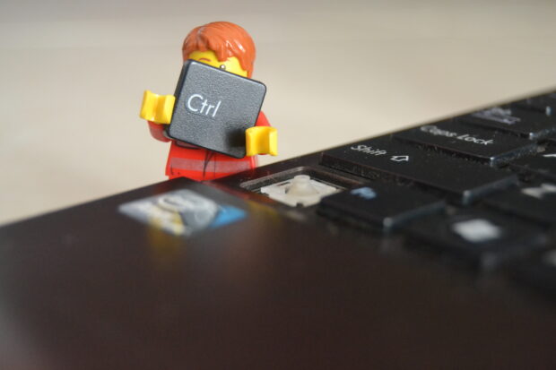 Lego worker holding a CTRL key detached from a laptop keyboard