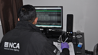 NCA officer on a computer displaying code