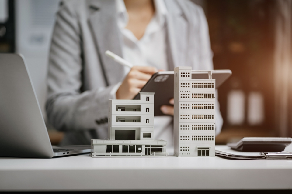 Business woman studying the data over a model of a house and block of flats.