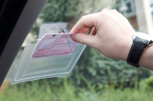 Hand placing PDI licence in holder on car windscreen