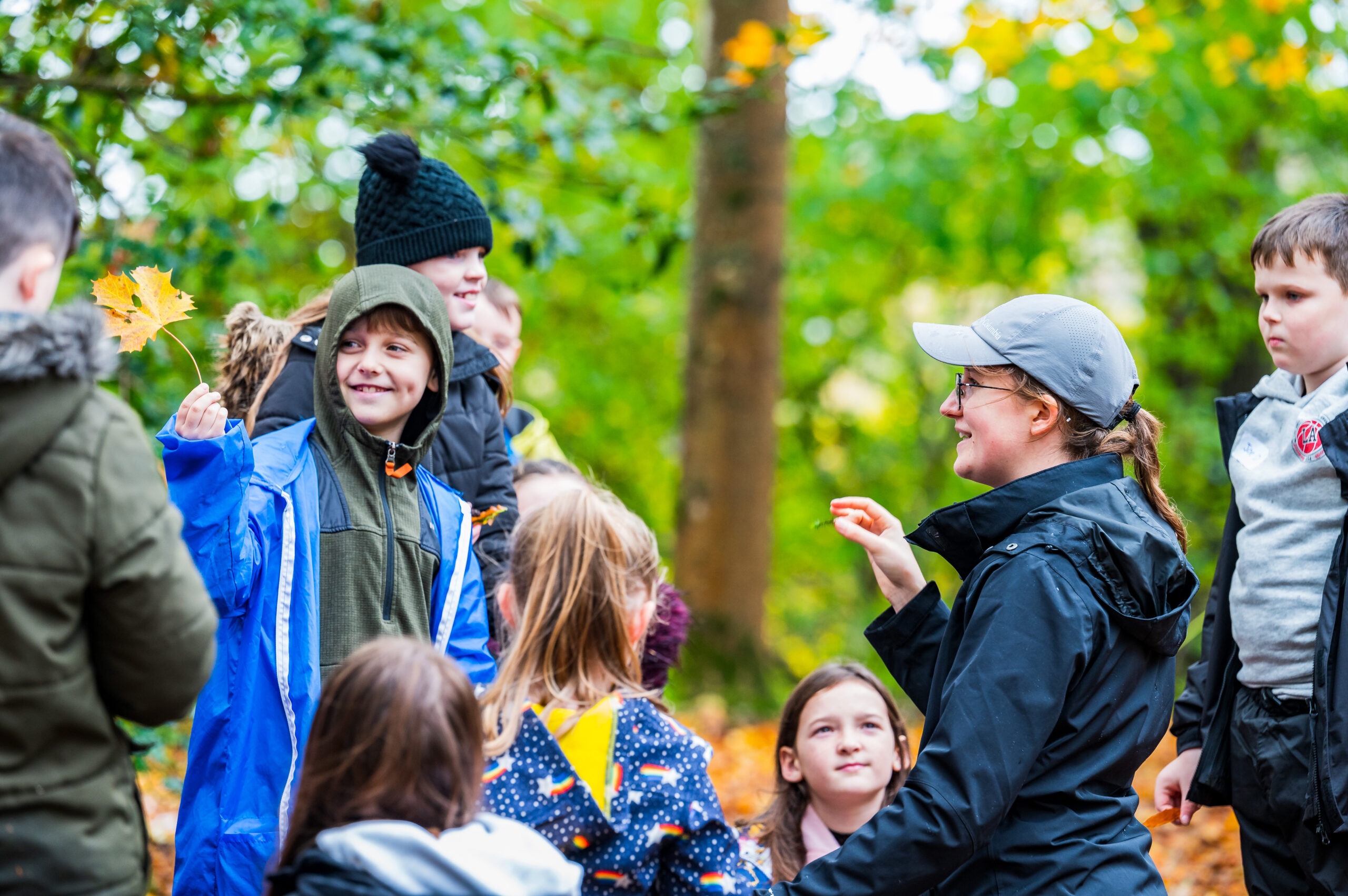 a group of children in a woodland looking at a teacher