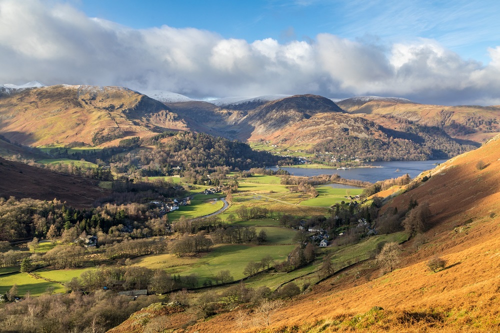 Aerial view overlooking Patterdale and Ullswater with bright blue sky
