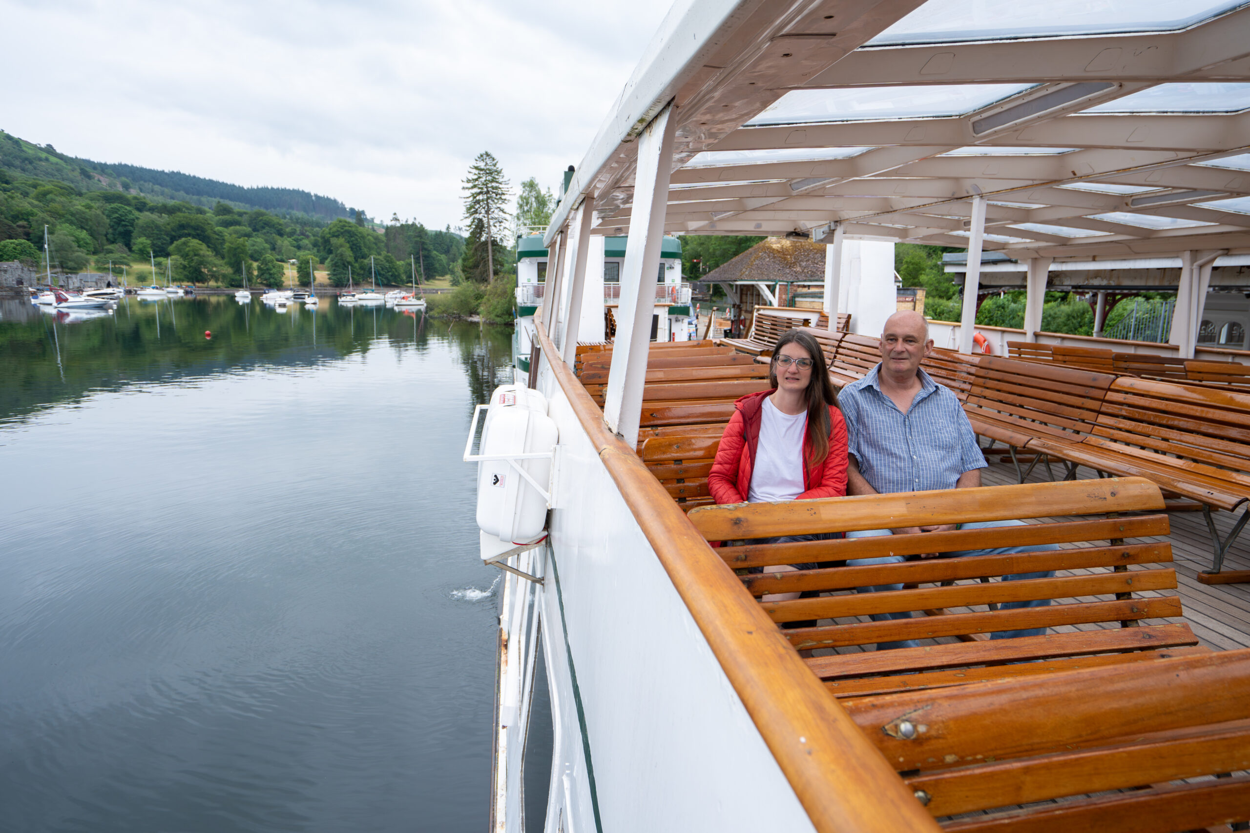 A man and women sat on a ferry looking out to Windermere