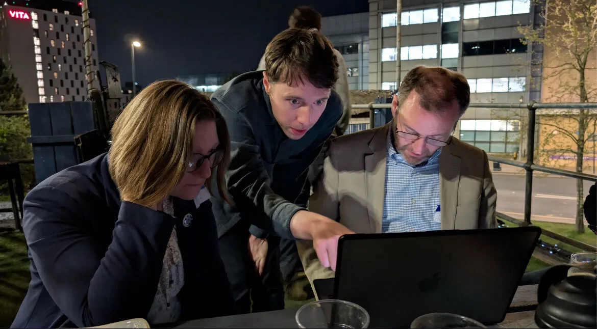 Three people looking at a laptop, working together on their solutions