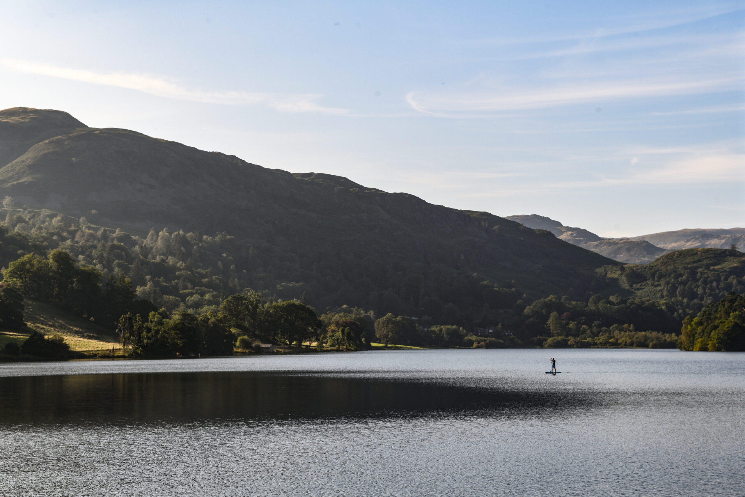 landscape view of lake on a sunny day with a distant paddle boarder