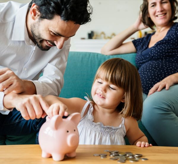 Family with a small child putting money into a piggy bank