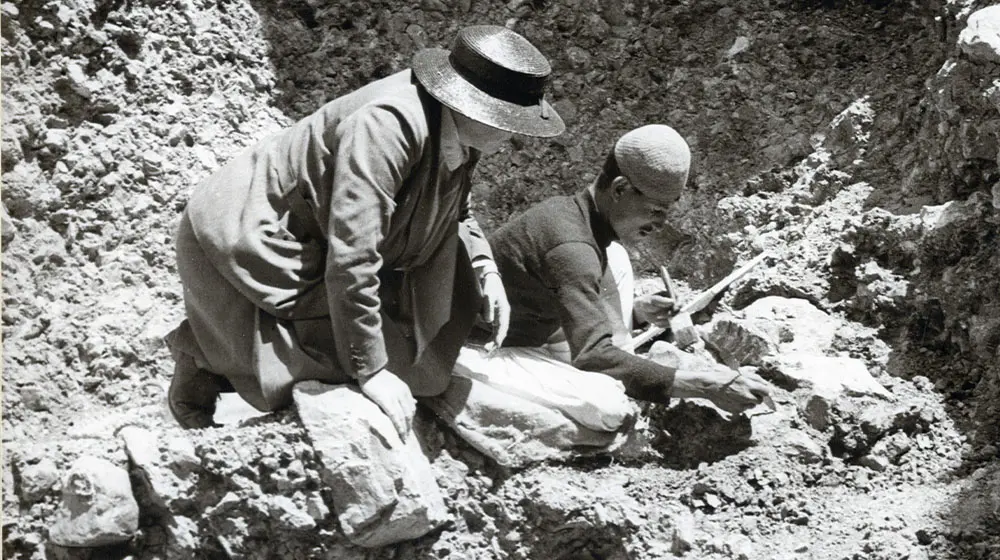 A black and white image of Dorothea Bate and a man at a rocky excavation site.
