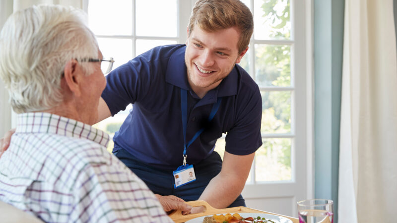 A care workers supporting a veteran in a care home.