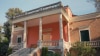 Entrance of a classical-style building with a wide staircase leading to a covered veranda with columns.