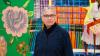 Lady wearing glasses in front of bright artwork.