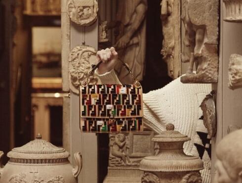 A woman wearing a brightly coloured bow against a marble mantlepiece and two rococo frames