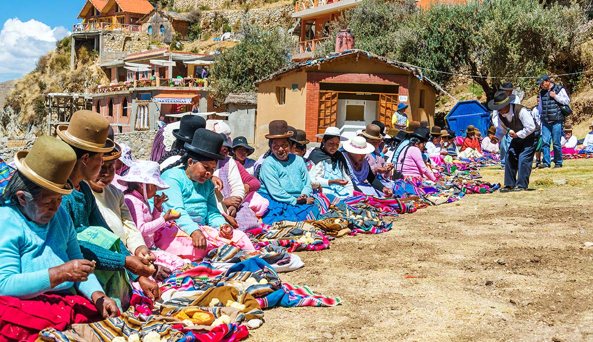 Aymara women sat on dusty ground in Bolivia.