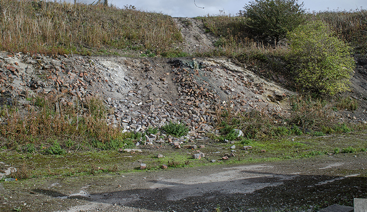 A mound of rubble and concrete with some weeds growing out of it 