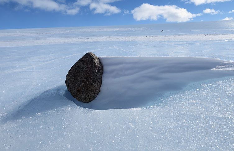 A dark rock frozen in place on ice
