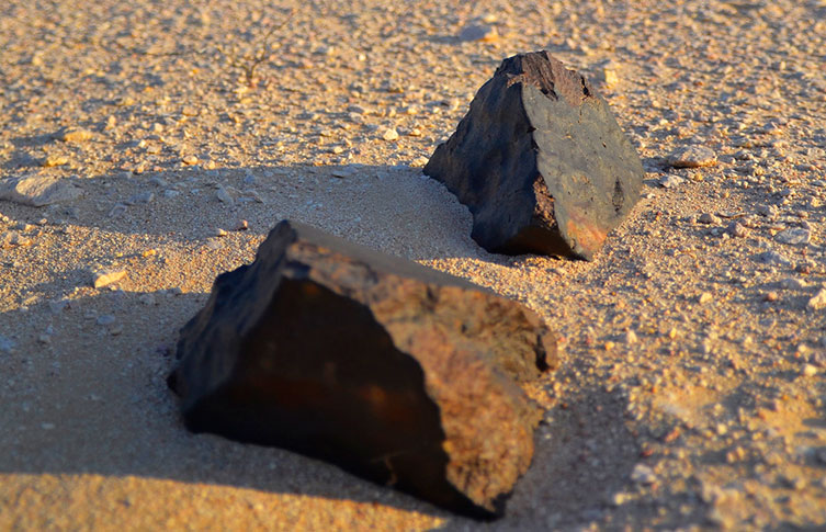 Two angular rocks sitting in sand