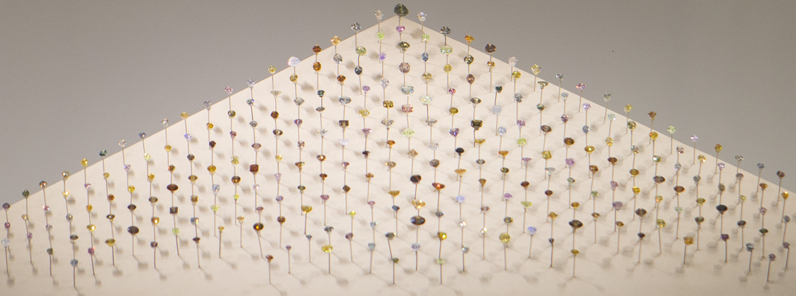 Lots of coloured diamonds - includinging yellow, pink, darker red and blue ones of different shapes and sizes - arranged in a triangle