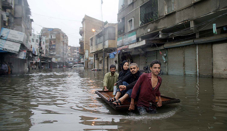 A family travels on a push-cart through a flooded street in Karachi