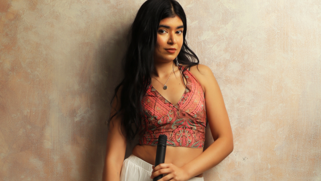 Close up of lady with long black hair holding a microphone by her waist.