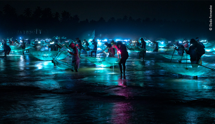 Fishermen at night time with nets hovered above the water