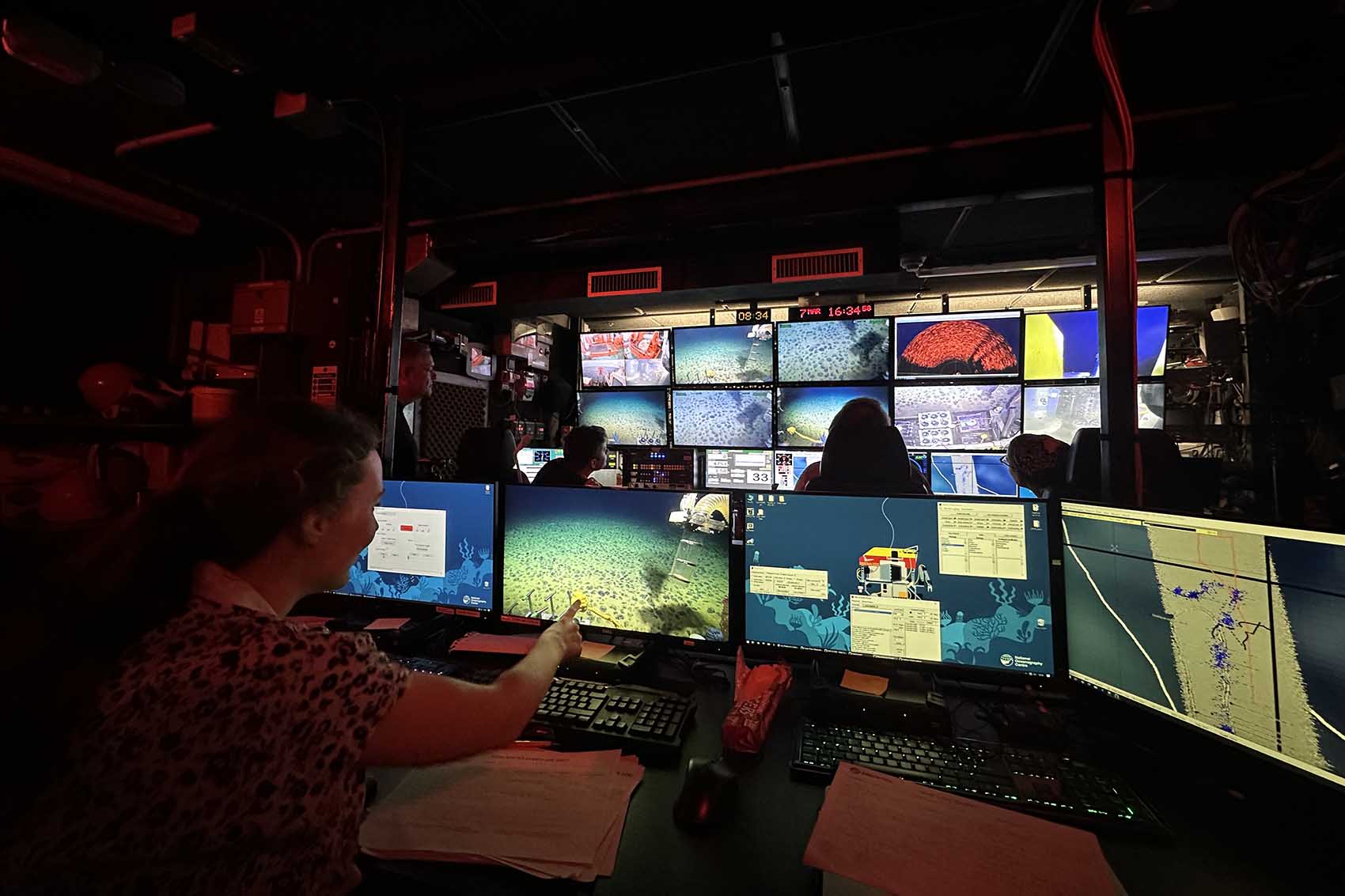 A picture from the research vessel showing a bank of 13 computer screens, each showing a different feed from a deepsea submersible.