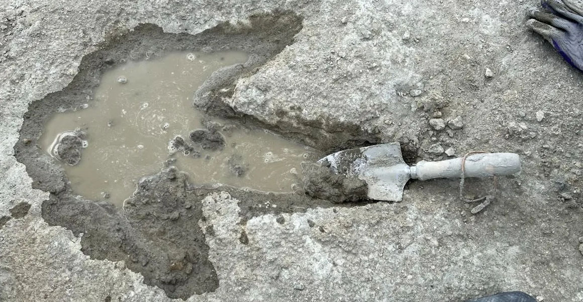 A large water-filled footprint with a trowl next to it for scale.