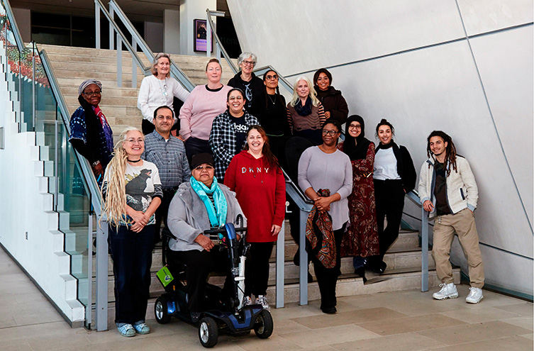 A group of people standing on some stairs, one person is on a mobility scooter