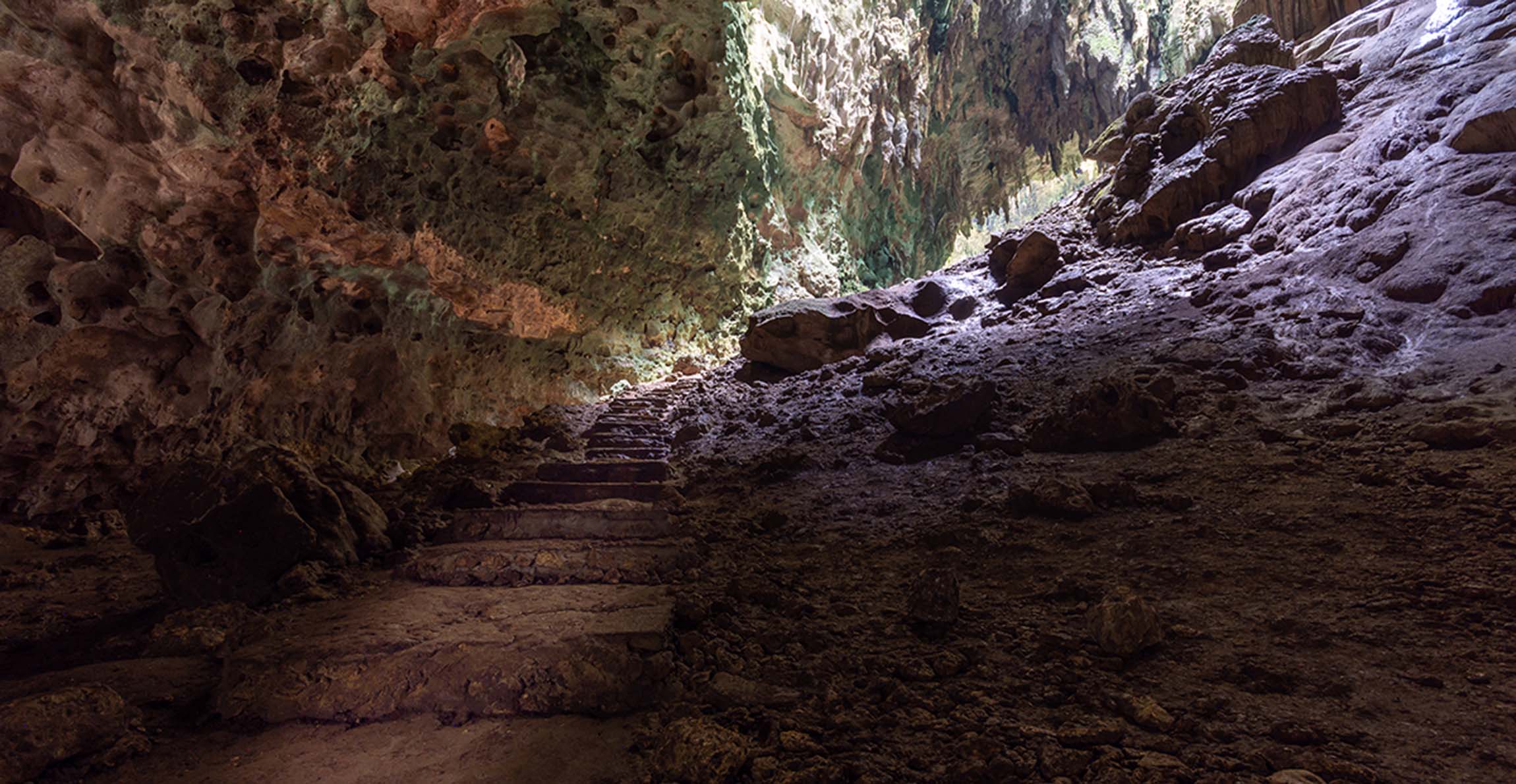 Stairs winding down a rocky slope inside Callao Cave.