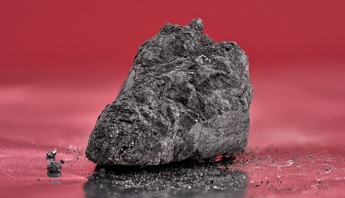 A small black meteorite sitting on foil