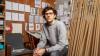 man with glasses wearing grey jumper sitting down