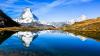snow covered mountain with blue sky and reflection in lake