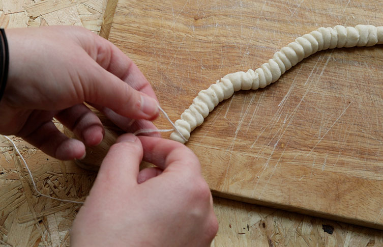 Making the ammonite's ribs by wrapping cotton around the salt dough and pulling it tight to make an indent