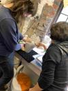 Two artists looking at a ceramic work in progress at a workshop.