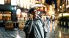 Man using smart phone in the old city street at night, talking on the phone and smiling