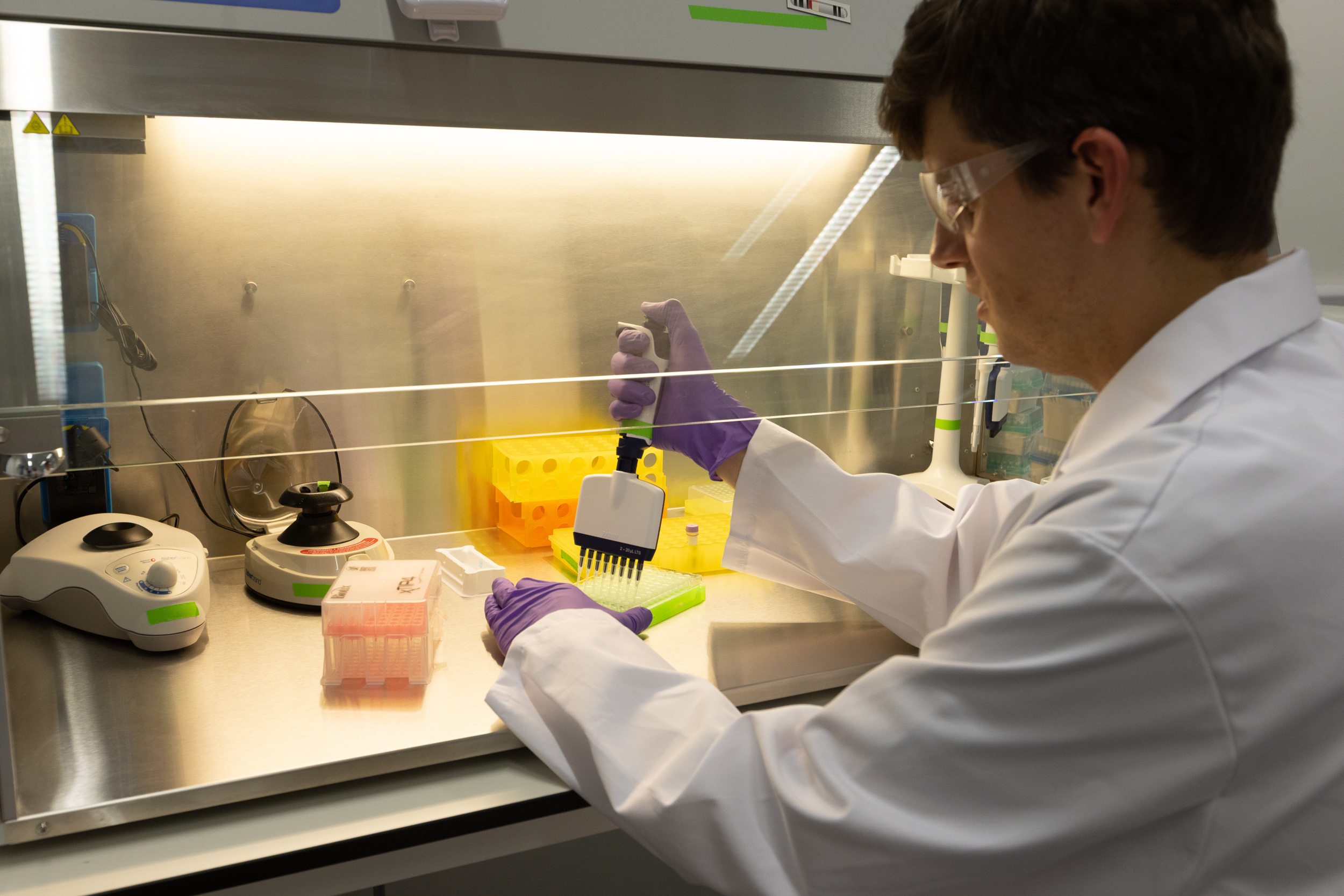 person using a pipette in a fume cupboard in a lab