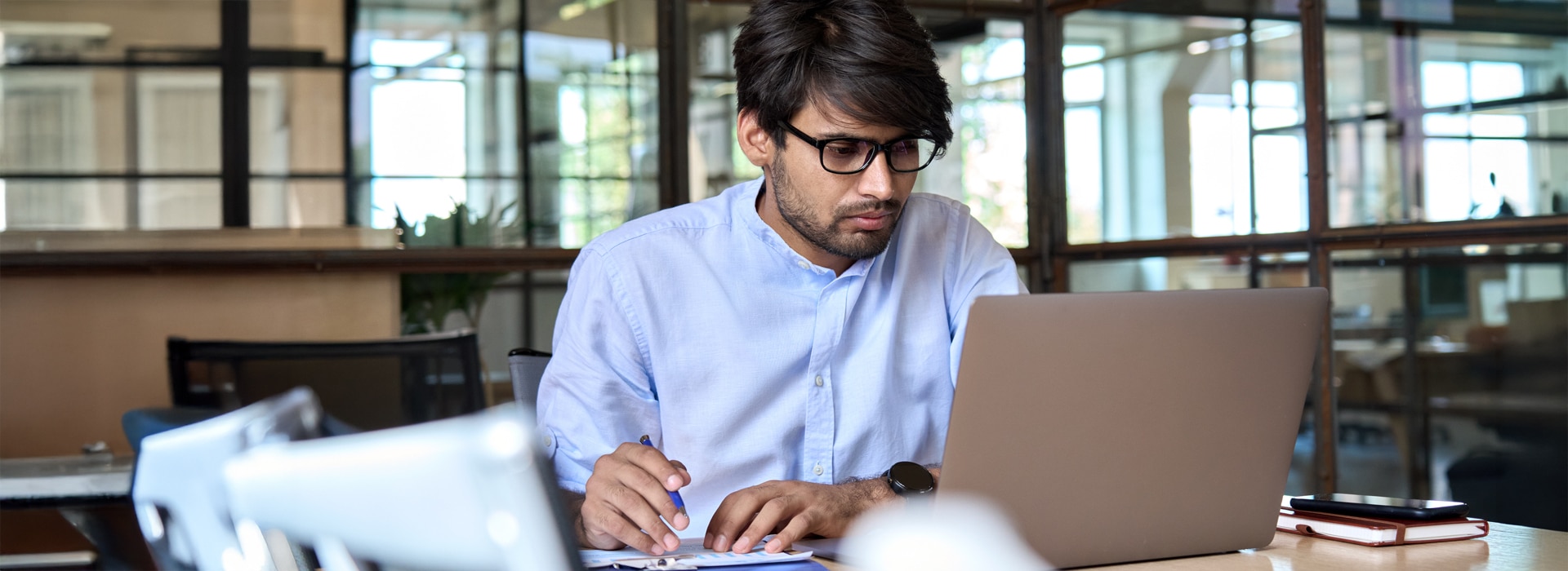 A man looking at a computer making notes