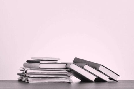 Stack of published advisory committee reports and documents on a desk.
