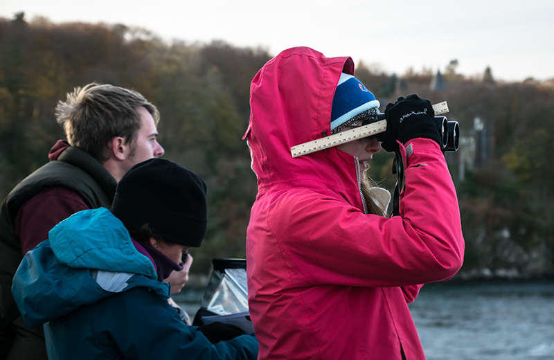 Photograph of a Volunteer Seabirds at Sea (V S A S) surveyor looking through binoculars